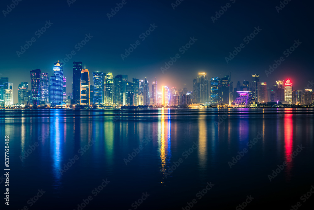 Night view on the centre of the city Doha, Qatar with many modern luxury building and skyscrapers illuminated with bright lights.