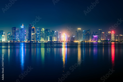 Night view on the centre of the city Doha, Qatar with many modern luxury building and skyscrapers illuminated with bright lights.