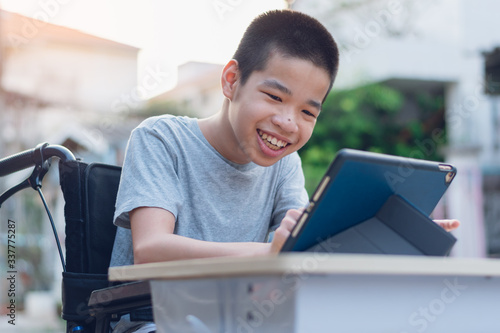 Disabled child on wheelchair happy time to use a tablet in the house, Study and Work at home for safety from covid 19, Life in the education age of special need kid, Happy disability boy concept. photo