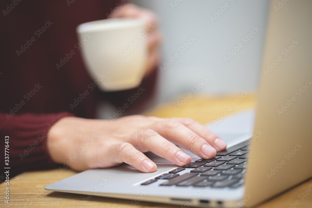 man working on a laptop computer and coffee cub. man working on a laptop computer and coffee cub.