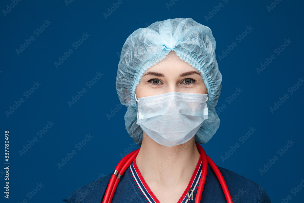 Stock photo portrait of a smiling doctor or nurse wearing face mask and hat. Isolate on blue background. COVID-19. Stock photo portrait of a smiling doctor or nurse wearing face mask and hat. Isolate on blue background. COVID-19.