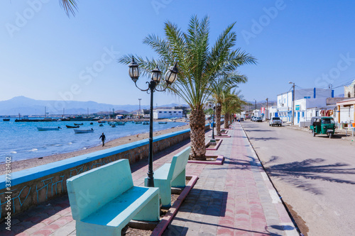 Tadjoura, Djibouti - November 09, 2019: Palms and Boats on the Sea Coastline under Blue sky photo