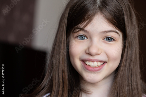 Closeup portrait of a young beautiful smiling brunette girl with big blue eyes. Close-up smile, malocclusion photo