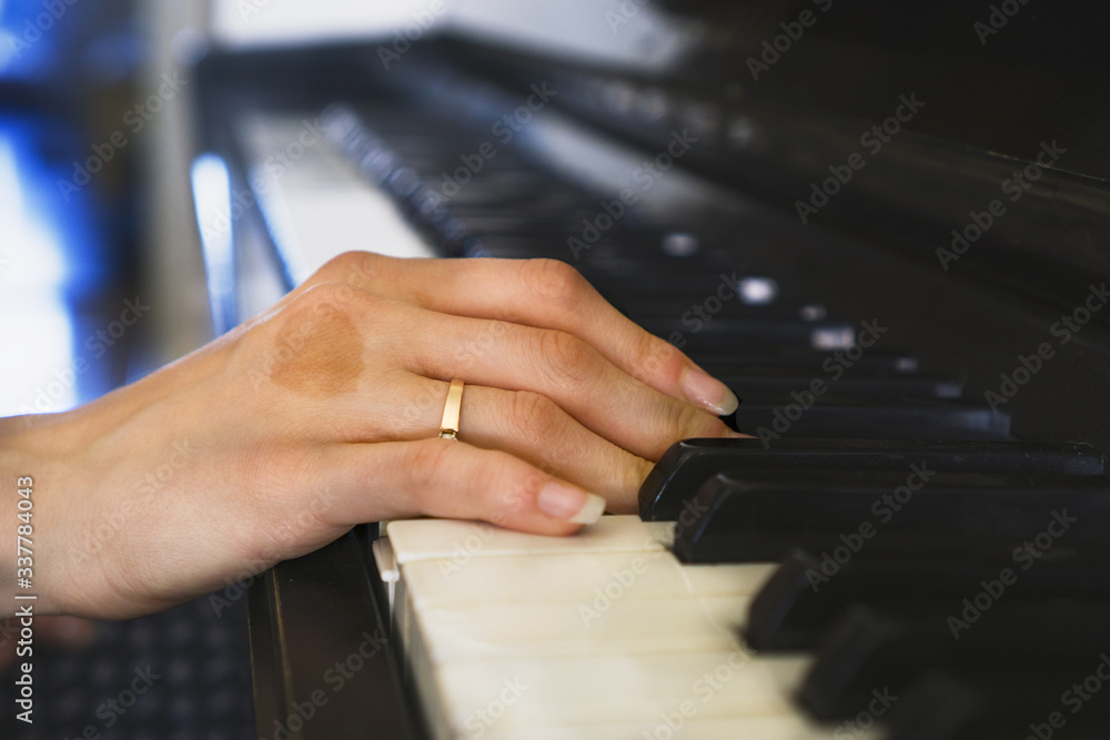 Obraz premium Girls hands on the keyboard of the piano. The girl plays piano,close up piano. Hands on the white keys of the Piano Playing a Melody. Womens Hands on the keyboard, Playing the Notes Melody