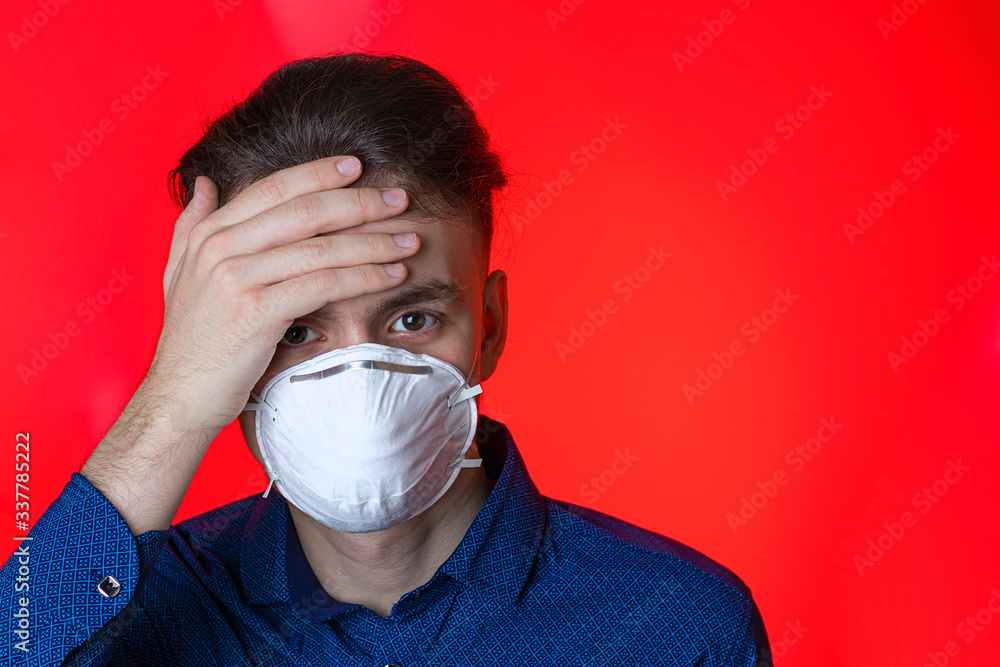 Virus-sick young man on self-isolation in a protective mask. Protects itself and others from the spread of coronavirus, on a red background Virus-sick young man on self-isolation in a protective mask. Protects itself and others from the spread of coronavirus, on a red background