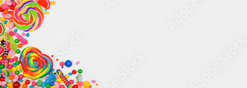 Colorful assorted candies. Overhead view corner border with a white banner background.