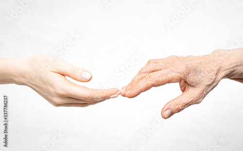 A young hand reaches for an old hand. Help for the elderly concept.