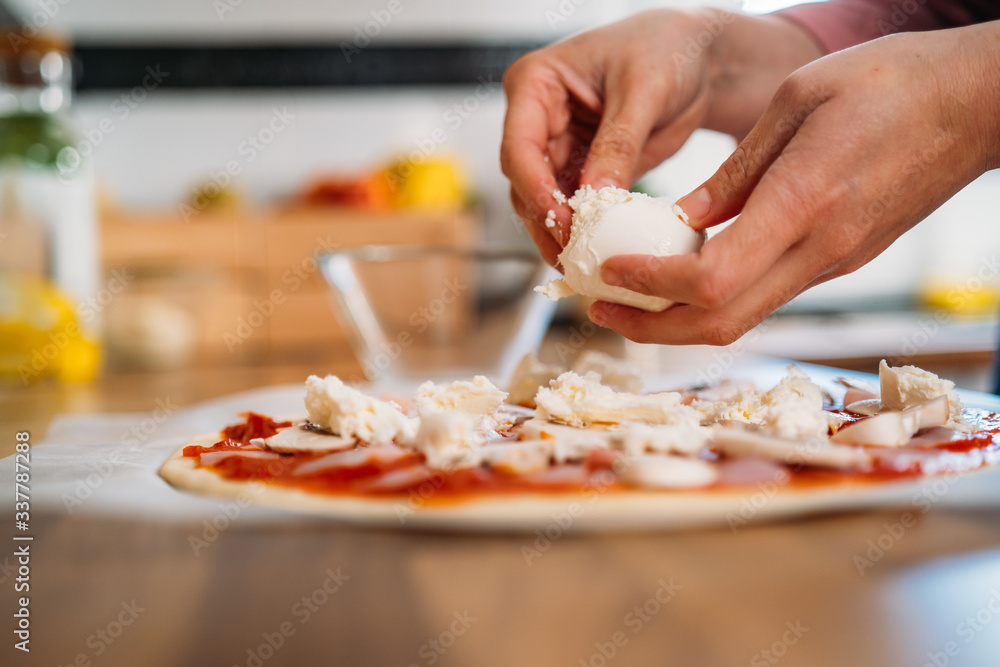 Woman's hands adding mozzarella cheese to a traditional margarita pizza. Preparation of a Original Italian pizza Woman's hands adding mozzarella cheese to a traditional margarita pizza. Preparation of a Original Italian pizza