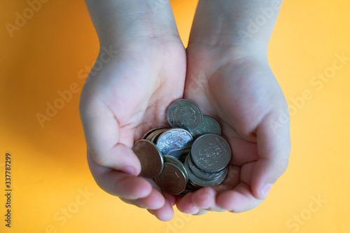 coins in the hands of a small child on a yellow background