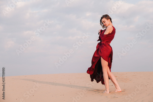 girl in the desert at sunset in a red dress developing in the wind