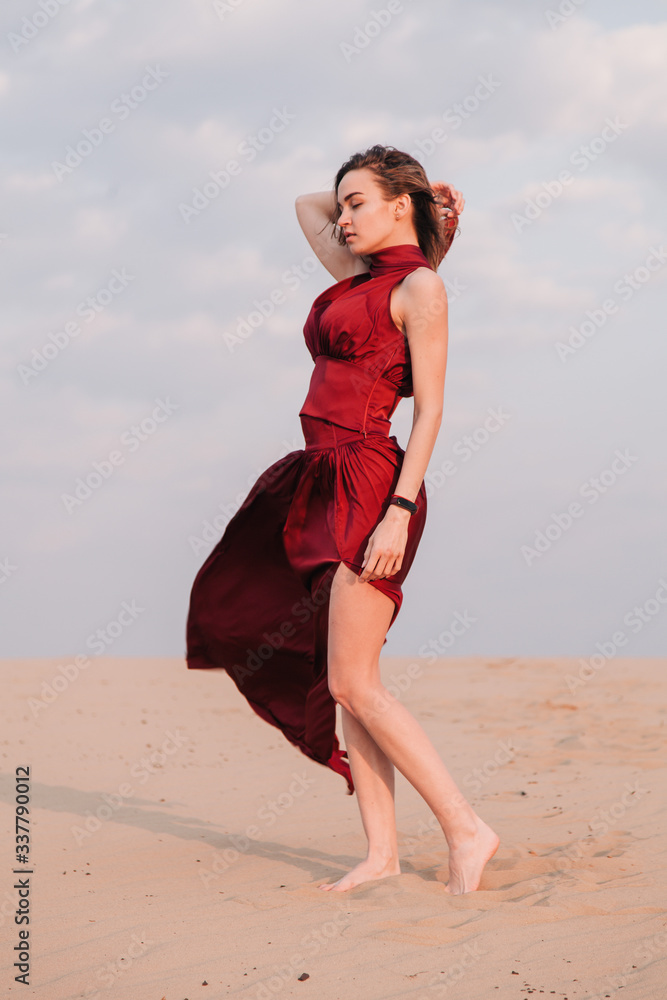 girl in the desert at sunset in a red dress developing in the wind