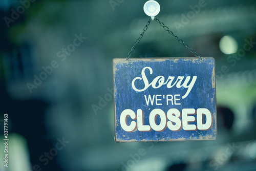 Blue closed sign in the window of a shop displaying the message "Sorry we are closed"