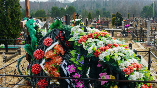 A wreath of arificial flowers on a new burial. Coronavirus concept.