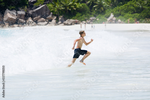 Young boy enjoys the summer holiday at beach  escaping from big splashing wave.