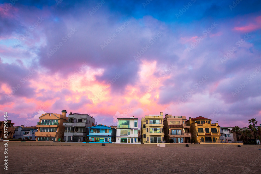 Obraz premium Dramatic storm clouds hover over the colorful beach cityscape of Hermosa Beach, California just after sunset.