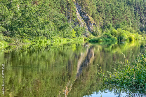 Landscape with forest, cliff and reflection in the river