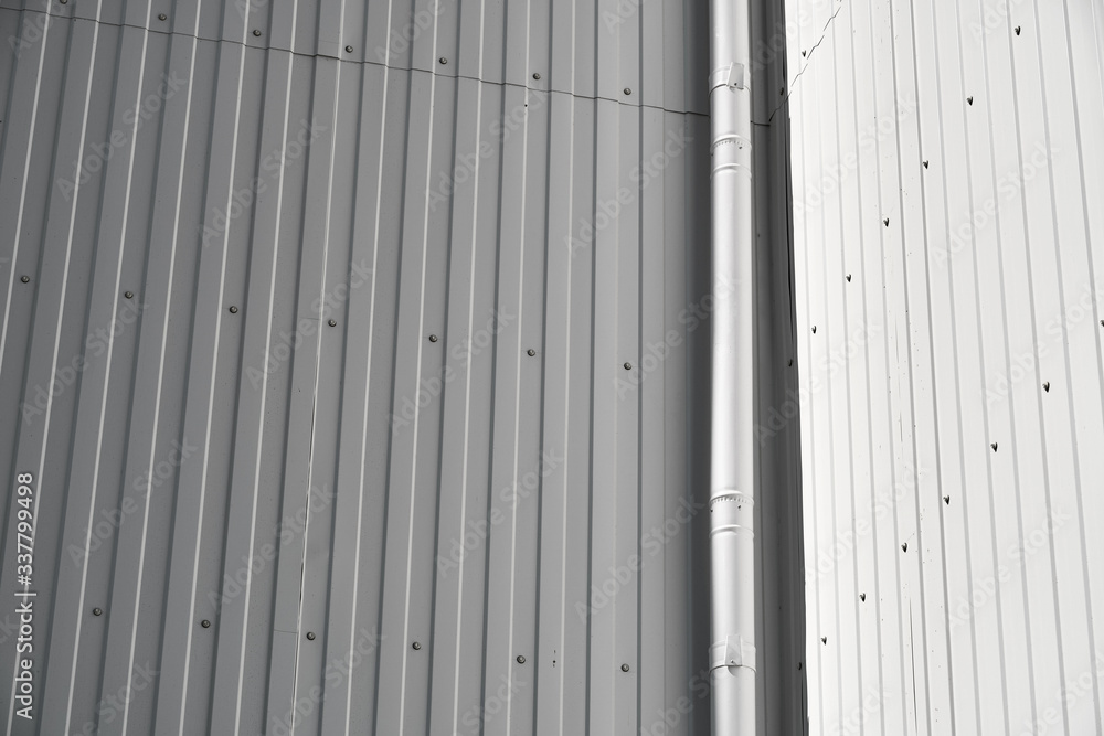 white metal siding on a wall and drain pipe as background white metal siding on a wall and drain pipe as background