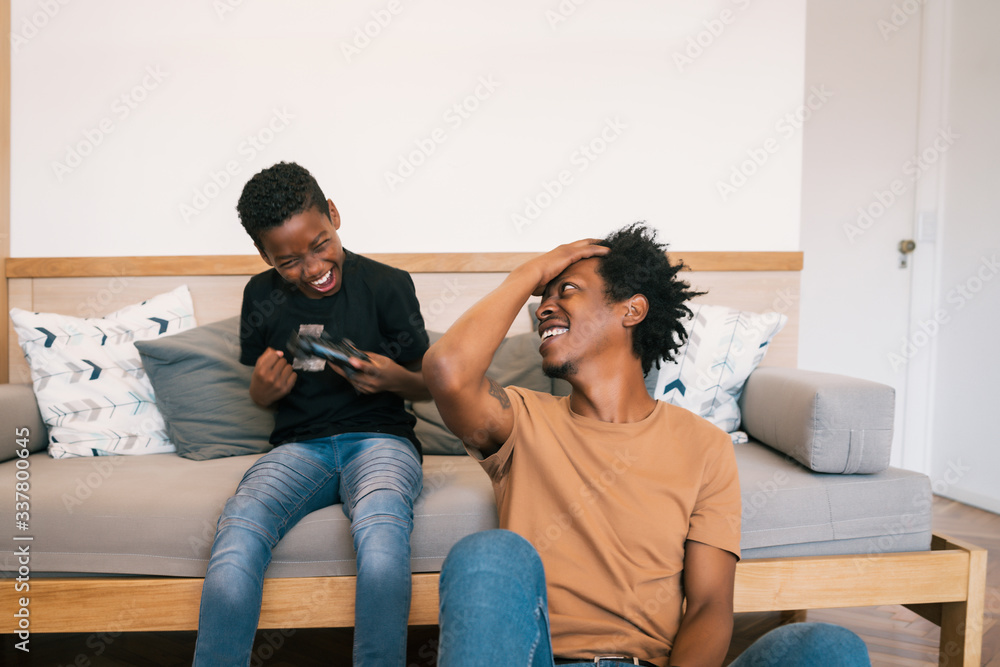 Father and son playing video games together at home. Father and son playing video games together at home.