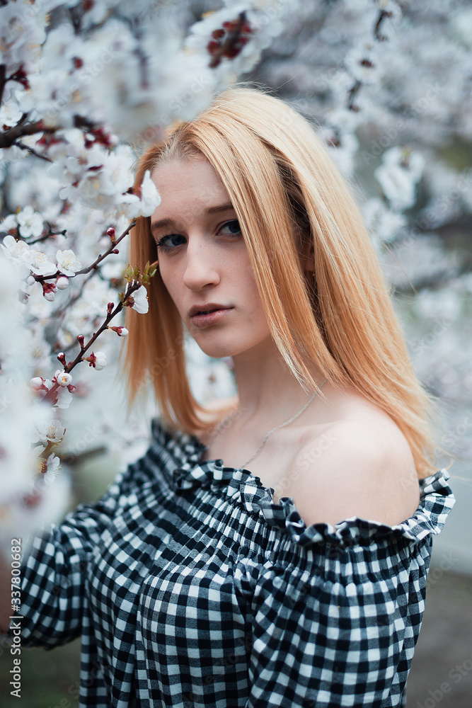 Beautiful young blonde girl on a background of flowering trees Beautiful young blonde girl on a background of flowering trees