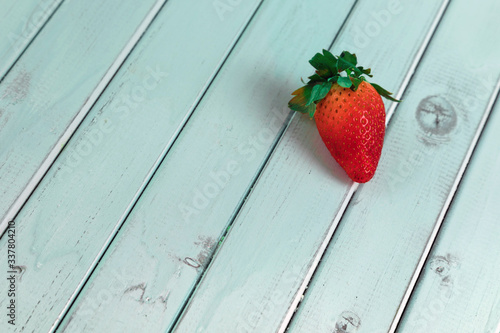 Red ripe strawberries lie on a light wooden table. Delicious berry on turquoise boards. The repeating diagonal lines of the boards.