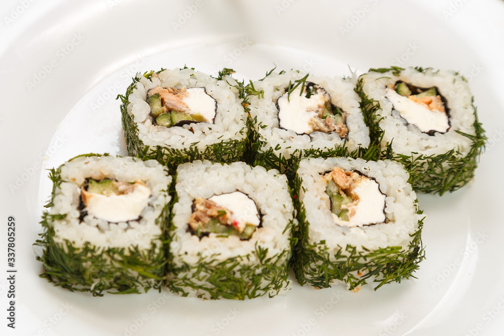 Rolls with salmon and dill on a white plate with chopsticks. Rolls with salmon and dill on a white plate with chopsticks.