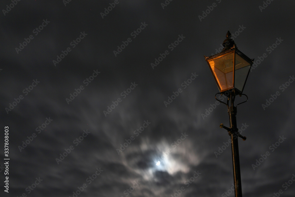 Unlit street lamp lantern with windy cloudy sky and moon