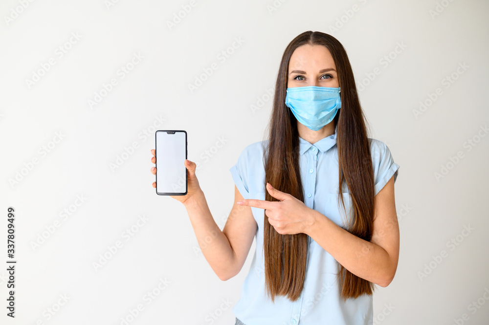Woman in medical mask demonstrates a phone screen Woman in medical mask demonstrates a phone screen