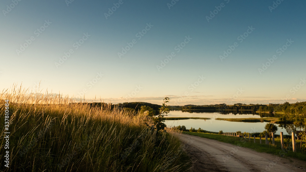 Sunset over the country road, meadow and lake. Poland Sunset over the country road, meadow and lake. Poland