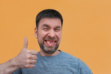 cheerful charismatic bearded young man with no front upper teeth gives a thumbs up