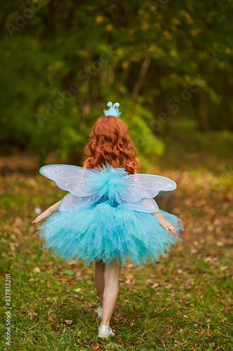 Young queen fairy with pink wings against a dark background waving a magic wand forward, fulfilling one's desires
