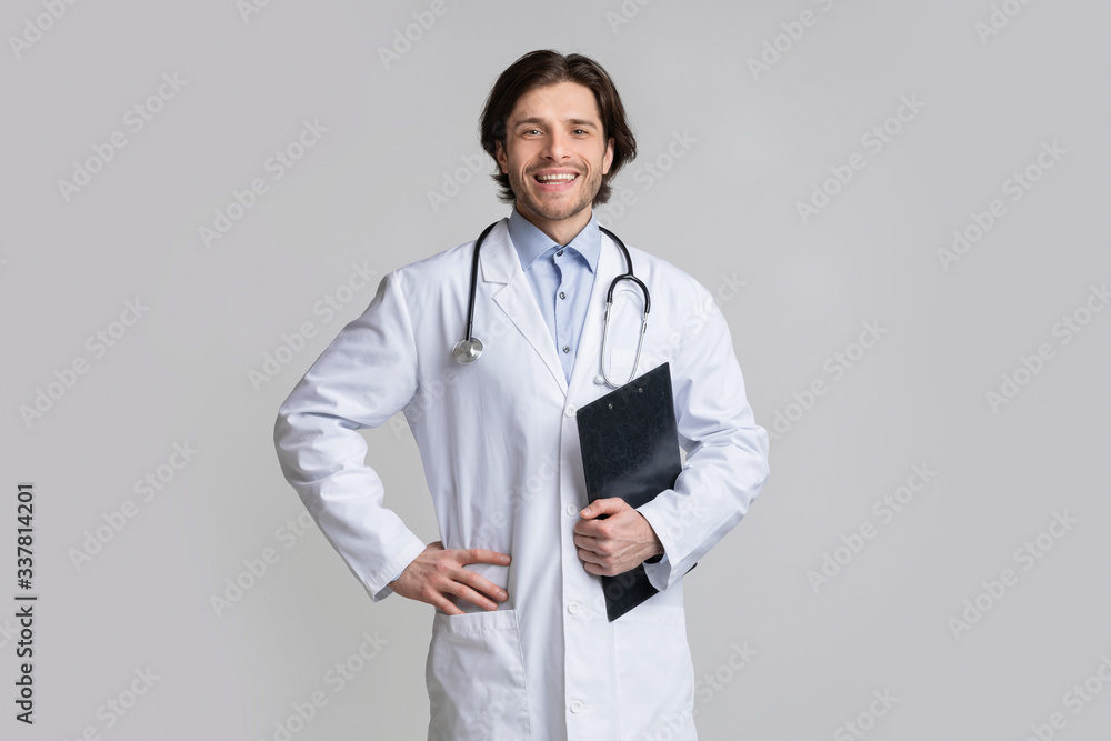 Confident smiling medical specialist with clipboard posing over light background Confident smiling medical specialist with clipboard posing over light background