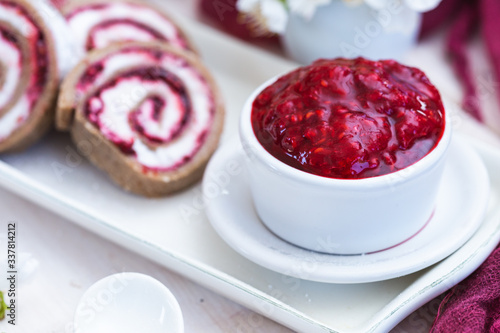 Raw raspberry jam in a white cup with raw raspberry rolls. Vegan food.