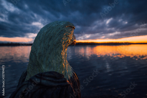 Wooden eagle looks atthe sunset next to the sea photo