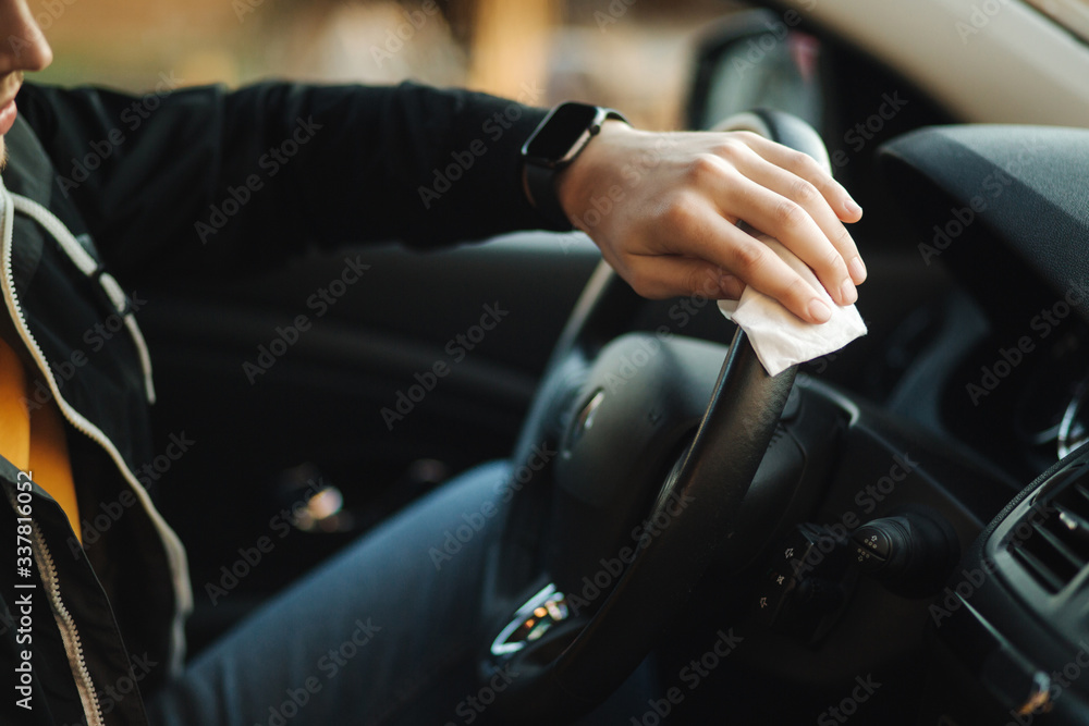 Man clean steering wheel using wet wipes. Man protect himself and clean car inside using antiseptic