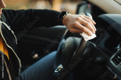Man clean steering wheel using wet wipes. Man protect himself and clean car inside using antiseptic © Aleksandr