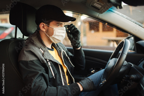 Man in car put on black gloves and medical mask to protect himself © Aleksandr