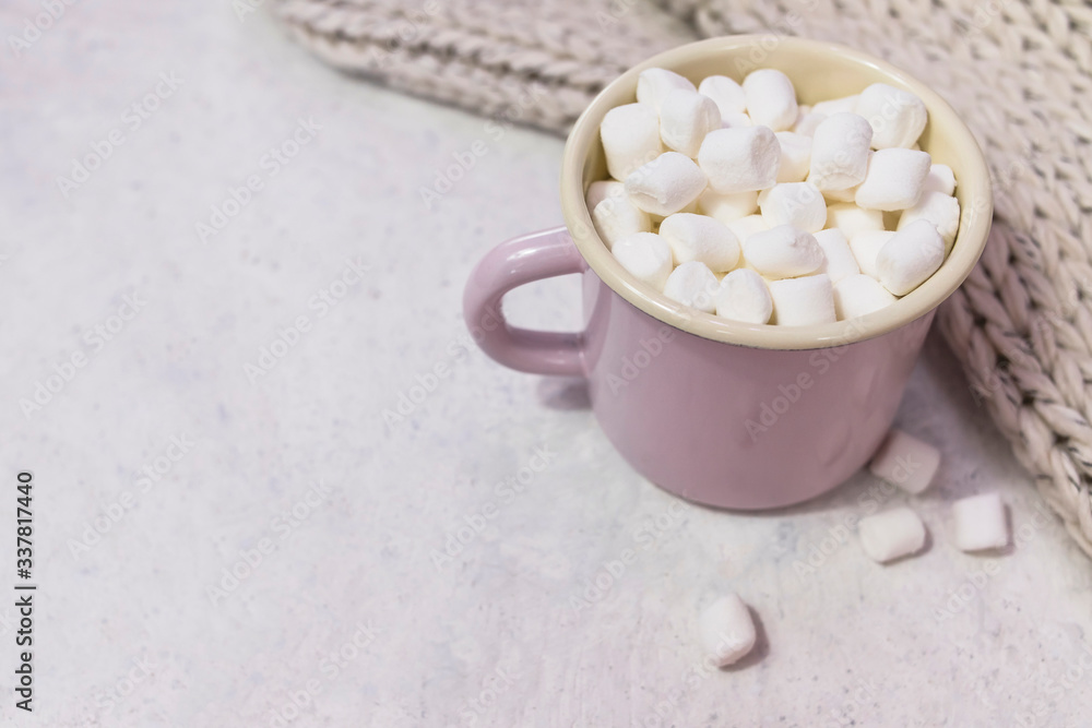 marshmallows in enameled mug on light coloured background marshmallows in enameled mug on light coloured background
