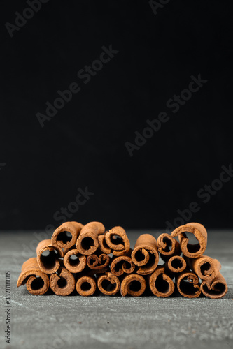 Closeup side view on brown natural fragrant cinnamon sticks on the grey background, vertical format