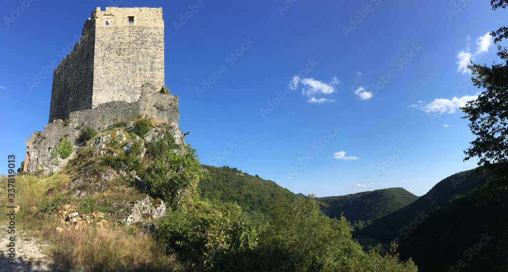 An ancient castle tower of stone overlooks a lush green Vally framed by a clear blue sky in Istria Croatia.   