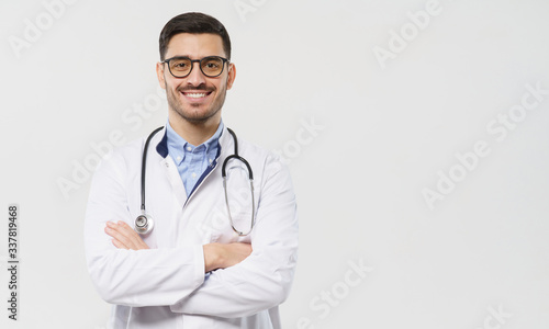 Horizontal banner of smiling young doctor ready to help patients with health problems, isolated on gray background with copy space on right side © Damir Khabirov