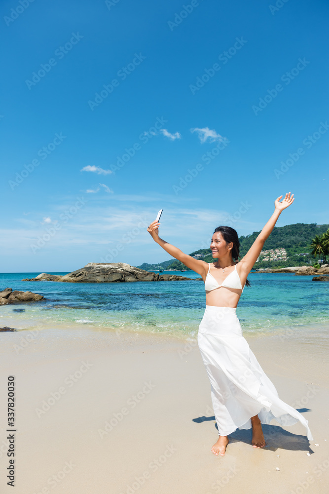 Happy Asian girl taking a self portrait photo, selfie, at the white sand beach. Copy space Happy Asian girl taking a self portrait photo, selfie, at the white sand beach. Copy space