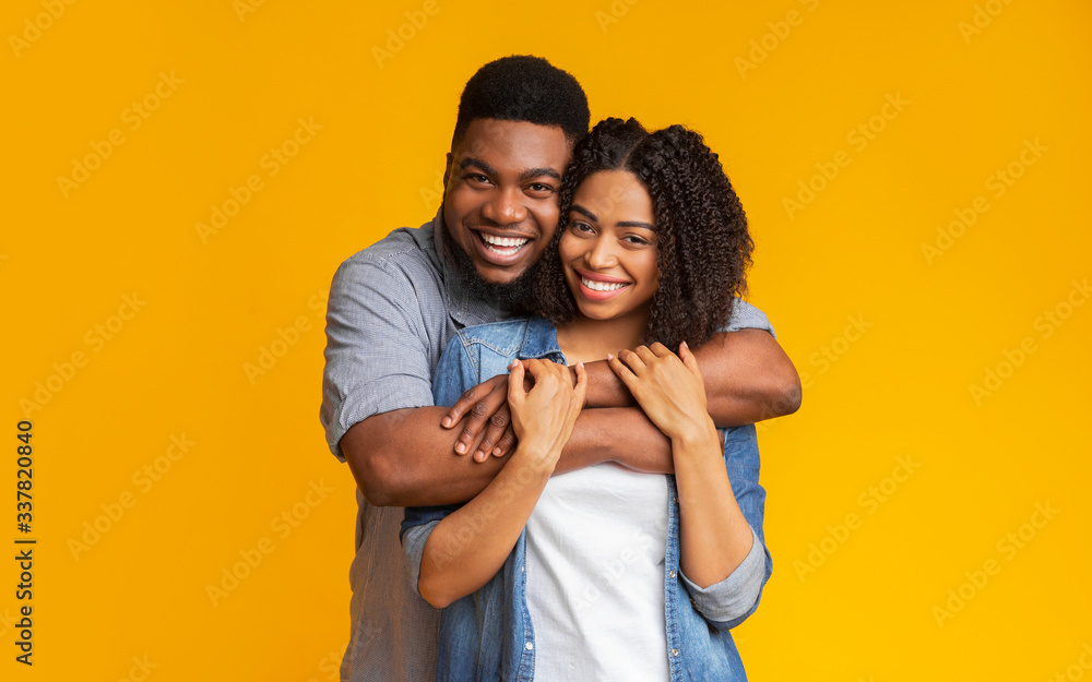Joyful african american sweethearts hugging and posing to camera Joyful african american sweethearts hugging and posing to camera