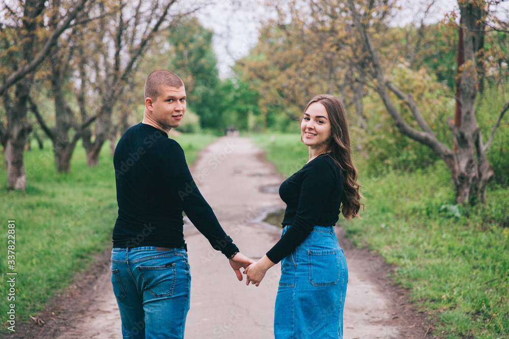 couple in blue jeans and black shirts in a green park couple in blue jeans and black shirts in a green park