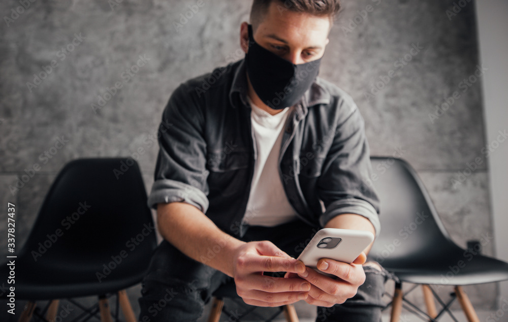 Young man with mask with smartphone on covid quarantine