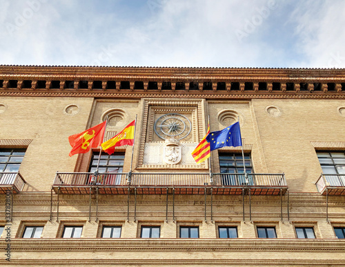 Fotografie The four flags of Europe, Spain, Aragon and Zaragoza at City Council in Plaza of Our Lady of the Pillar, in a sunny day with blue sky