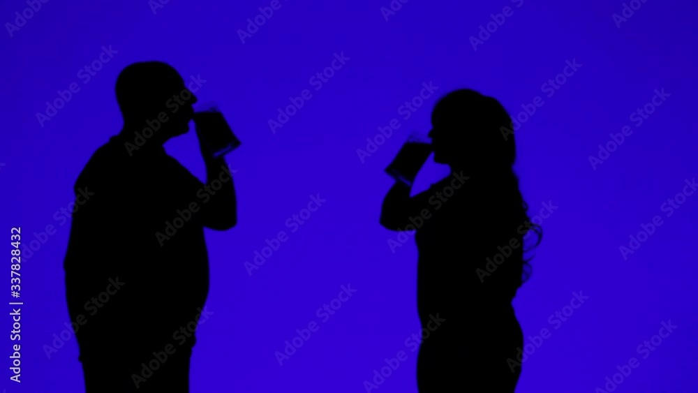 Silhouette of a woman and a man drinking beer from mugs on a blue background Silhouette of a woman and a man drinking beer from mugs on a blue background
