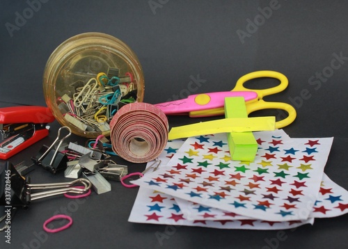 Messy School stationaries & other Equipments on a black background. stickers, staplers, sissors, sticky notes, pins, meassuring tapes and other tools.  photo