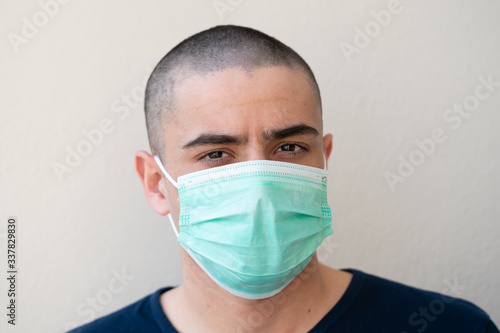 Portrait of young man, takes off the medical flu mask, on background of white color...