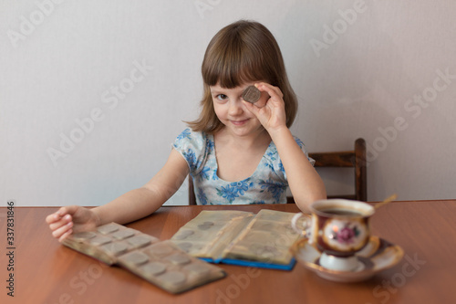 Girl numismatist plays with a coin