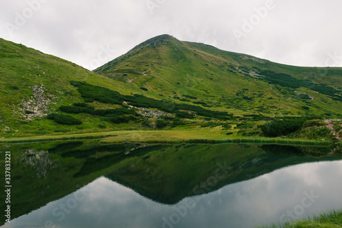 Carpathians mountains in the middle of summer. Nesamovite lake on the top of hill. Green hill. Ukrainian popular tourism place with calm water and shrubs. Mountain hiking. Walking on the top. View.